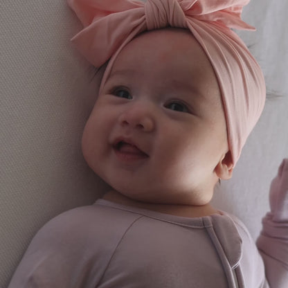 Baby wearing lavender pyjama laying down playing